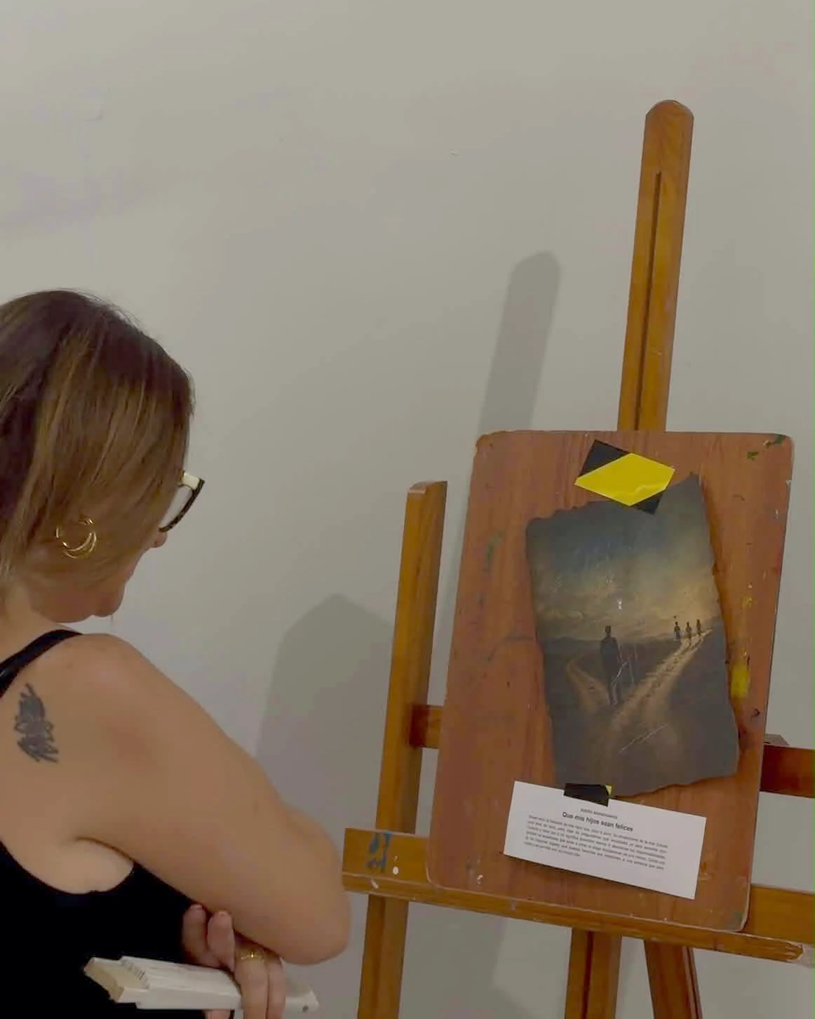 Visitante leyendo una obra presentada sobre un caballete