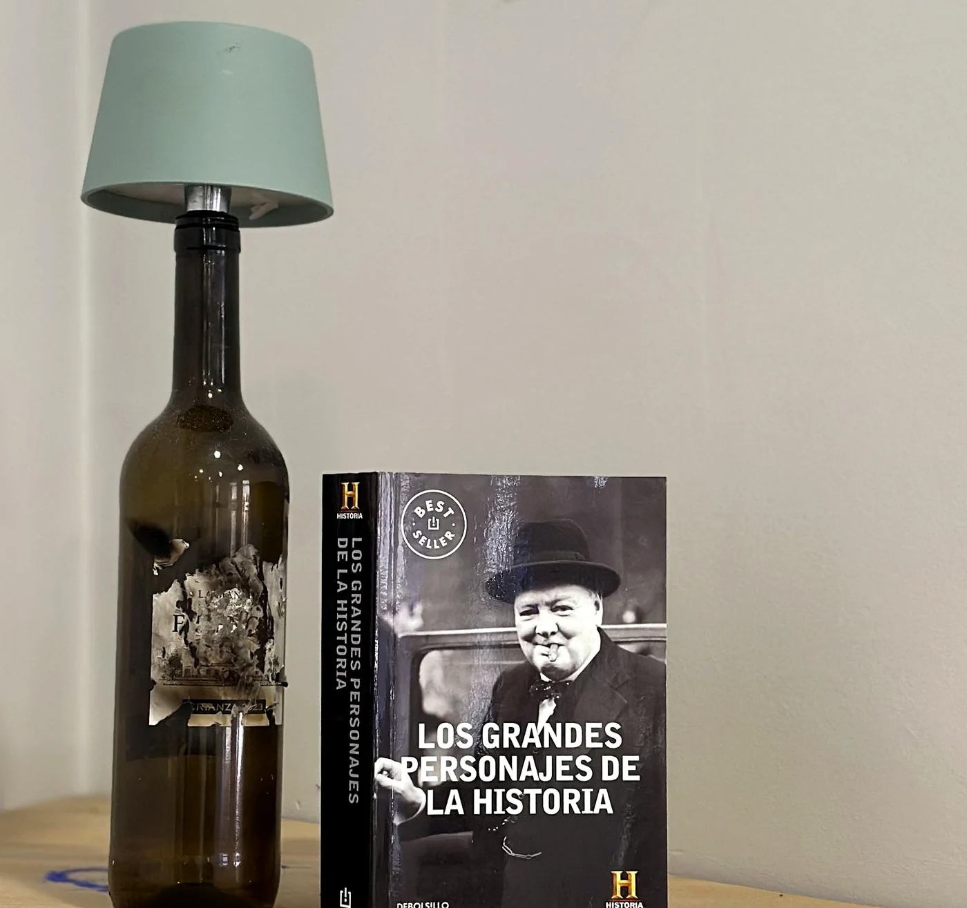 Botella convertida en lámpara junto a un libro de historia